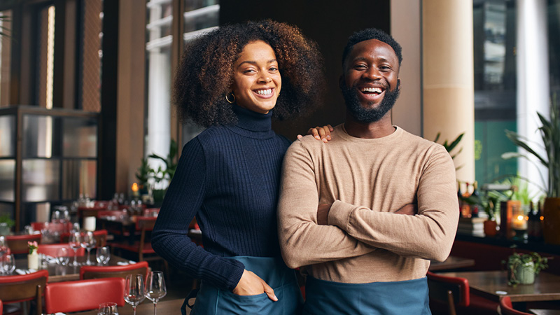 a man and woman standing side by side, smiling. 